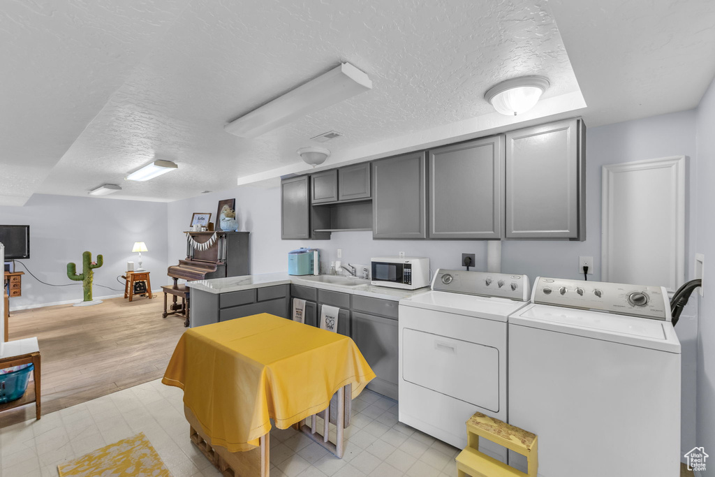 Laundry room with separate washer and dryer, a textured ceiling, and baseboards