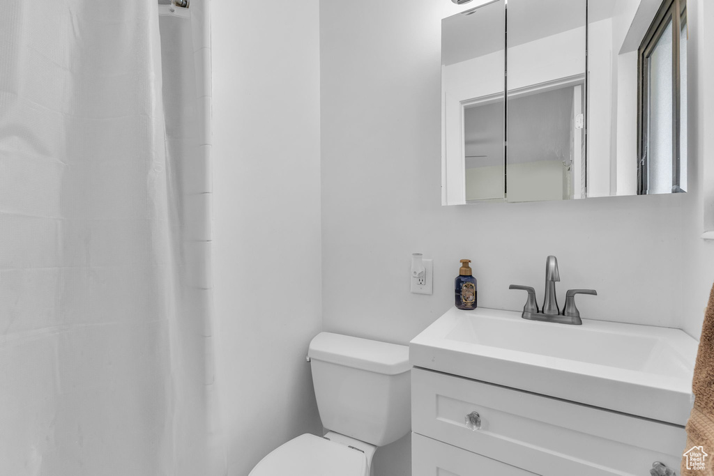 Bathroom featuring toilet, vanity, and a shower with curtain