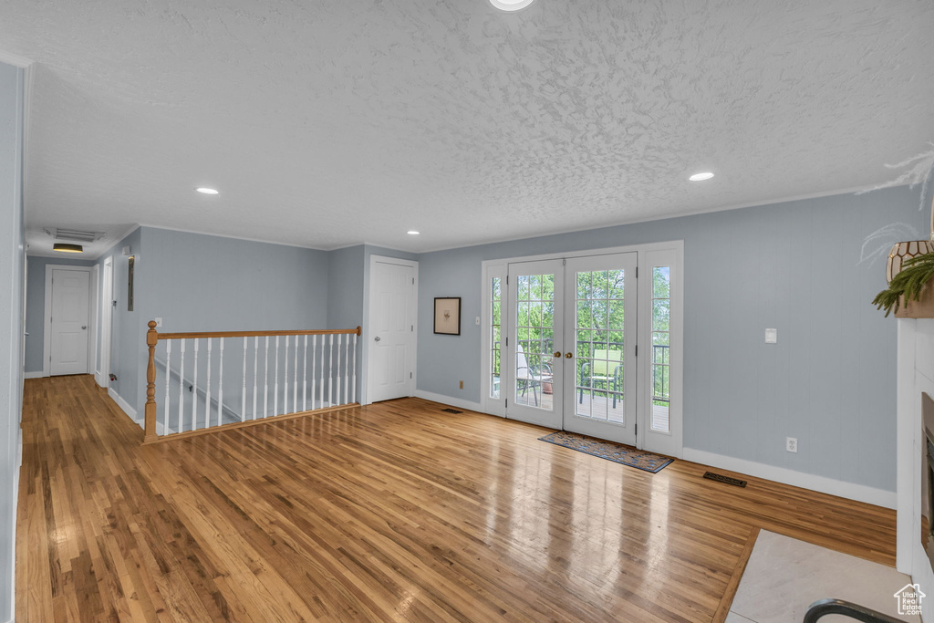Unfurnished room featuring wood finished floors, baseboards, a textured ceiling, recessed lighting, and french doors