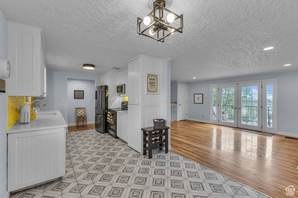 Kitchen featuring appliances with stainless steel finishes, a sink, a textured ceiling, light wood-style flooring, and light countertops