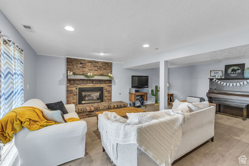 Living room featuring a fireplace, recessed lighting, a textured ceiling, and light wood-style floors