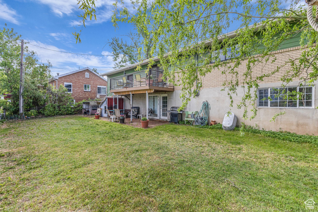Rear view of house with a yard, stucco siding, and a deck