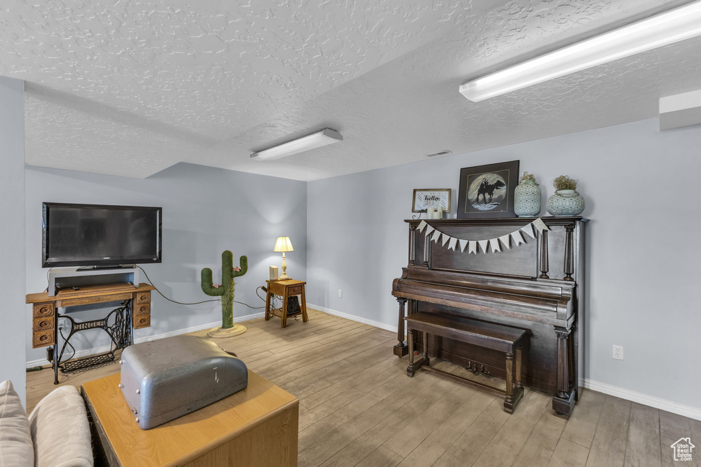 Living room featuring a textured ceiling, wood finished floors, and baseboards