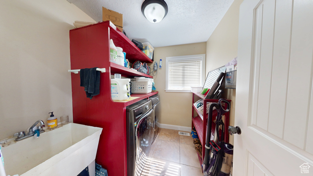 Washroom featuring separate washer and dryer, baseboards, light tile patterned floors, and a textured ceiling