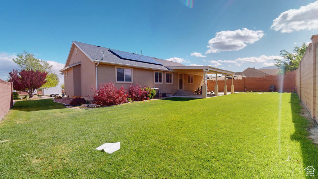 Back of property featuring solar panels, stucco siding, and a shingled roof