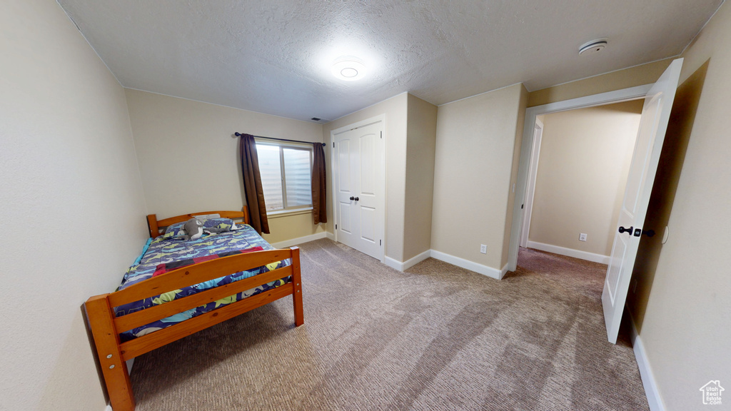 Carpeted bedroom with a textured ceiling and baseboards
