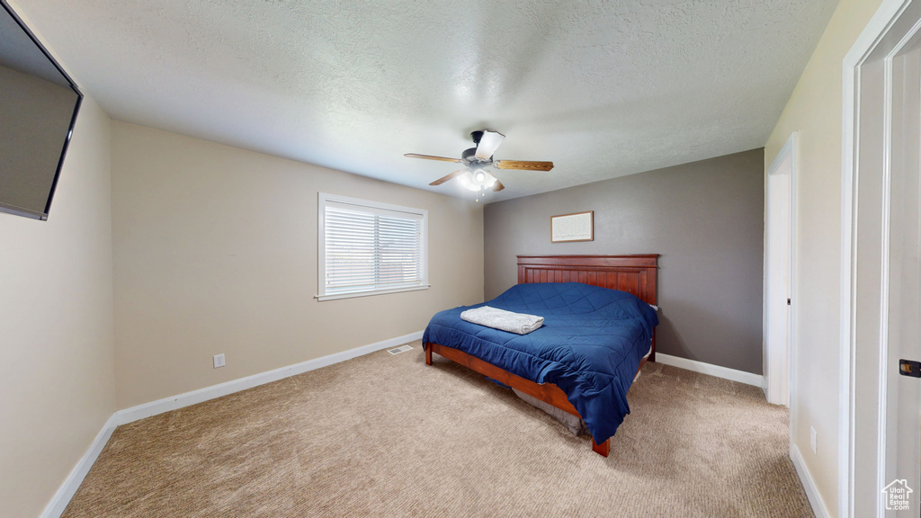 Carpeted bedroom featuring baseboards, a textured ceiling, and a ceiling fan