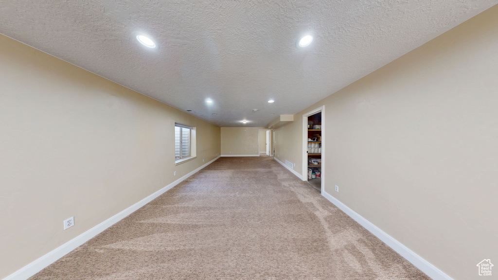 Basement featuring light colored carpet, recessed lighting, a textured ceiling, and baseboards