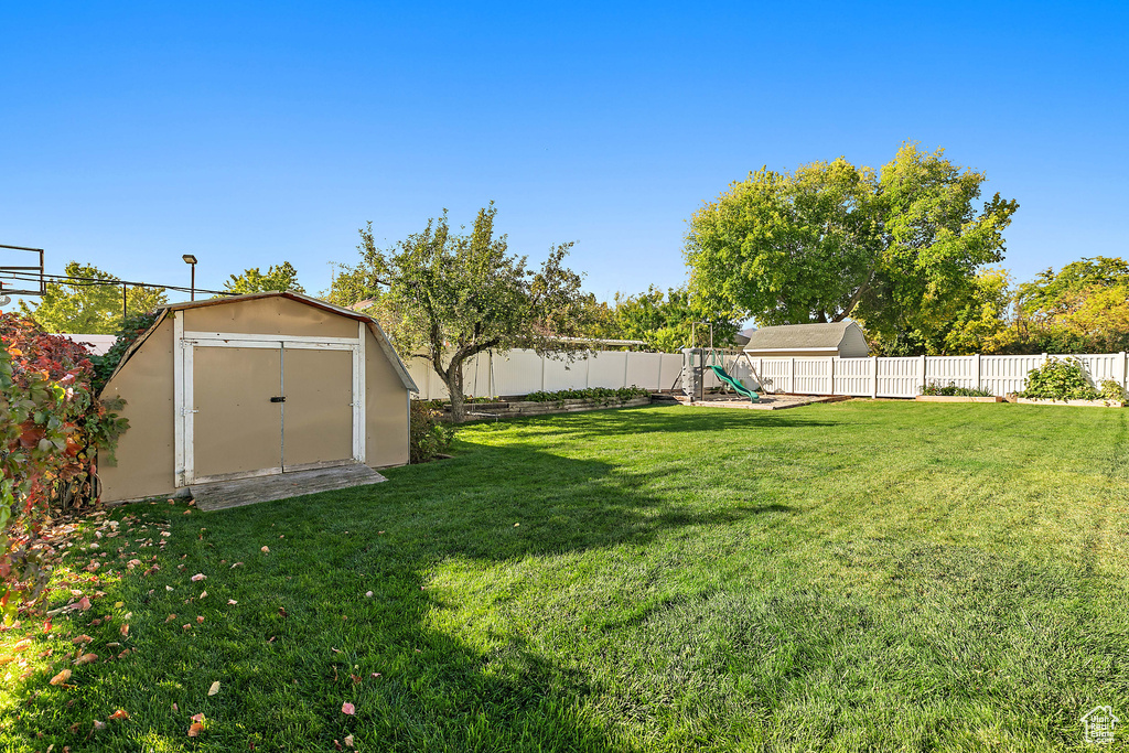 View of yard with a storage shed, a playground, and an outbuilding