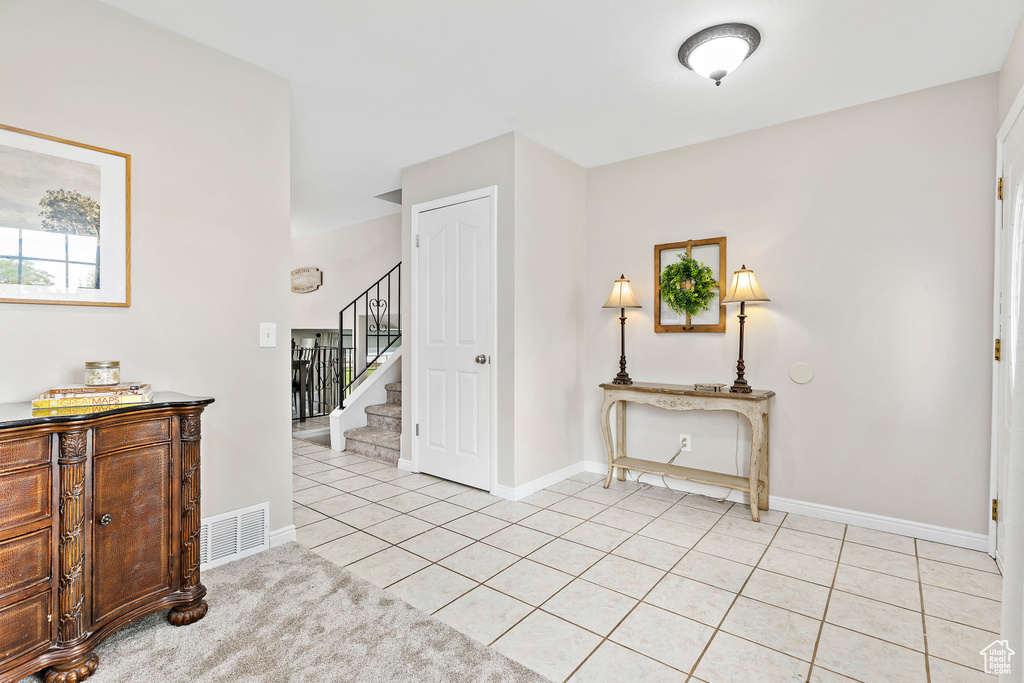 Foyer entrance with stairs, light tile patterned flooring, and baseboards