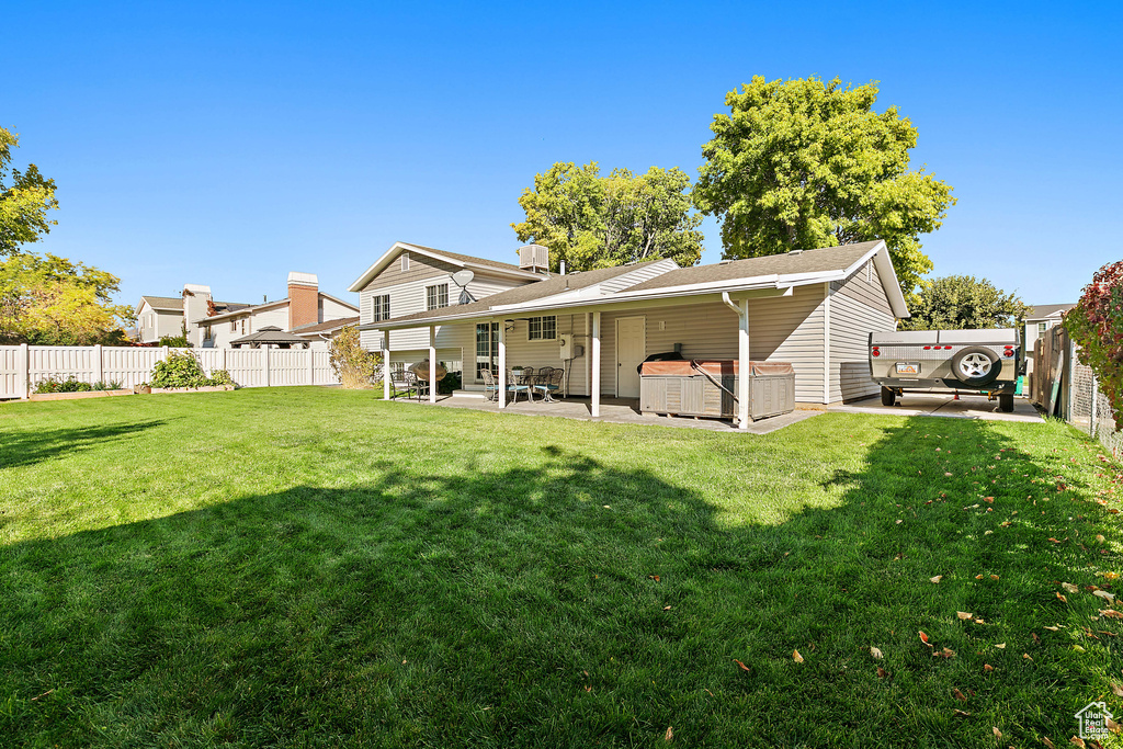 Back of property with a hot tub and a patio