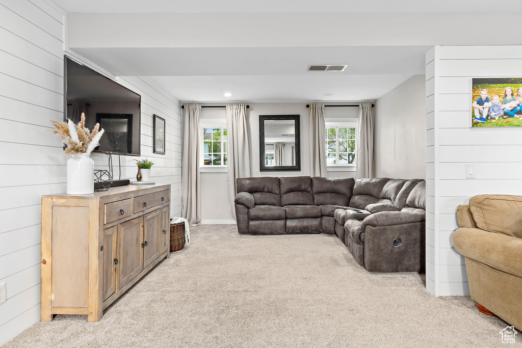 Living room with light carpet, wood walls, and recessed lighting