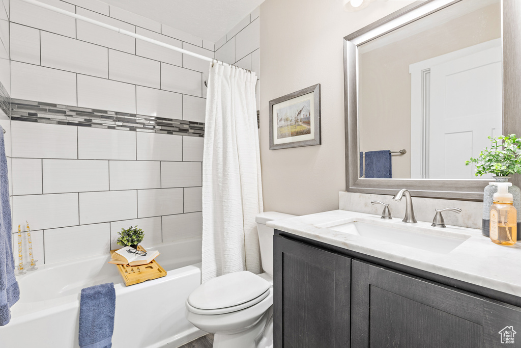 Full bath with toilet, shower / bath combination with curtain, and vanity