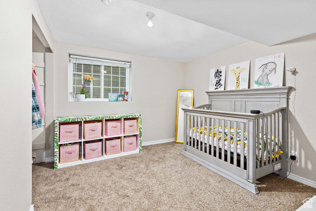 Bedroom with carpet floors, baseboards, and a crib