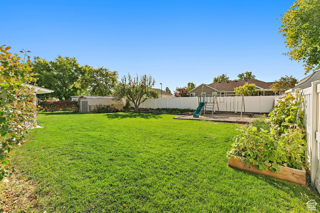 View of yard featuring a playground, a storage shed, an outbuilding, and a vegetable garden