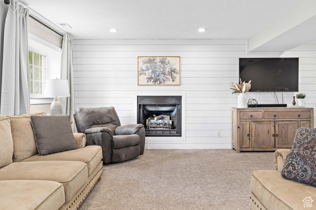 Living room featuring carpet, a fireplace, wooden walls, and recessed lighting