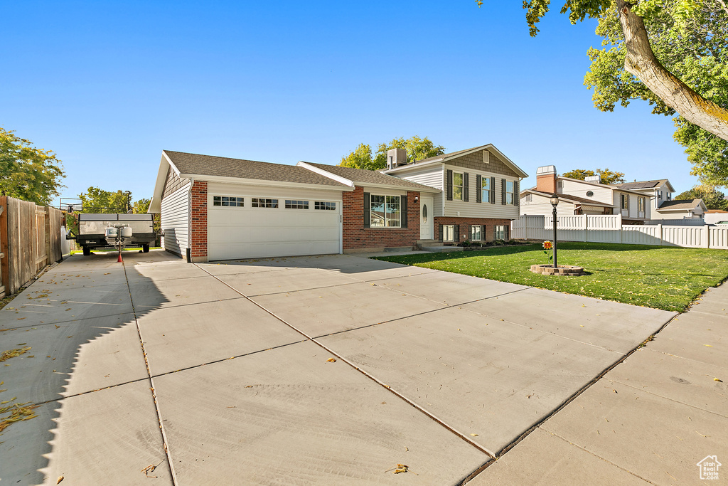 Tri-level home featuring a garage, brick siding, concrete driveway, and a shingled roof