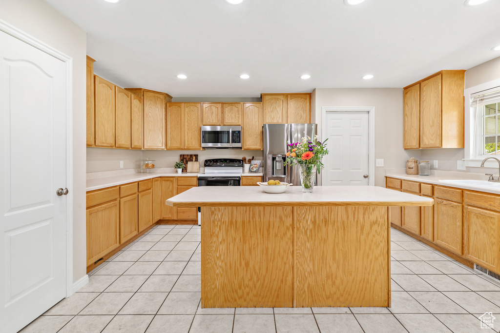 Kitchen featuring appliances with stainless steel finishes, a sink, light tile patterned floors, light brown cabinetry, and recessed lighting