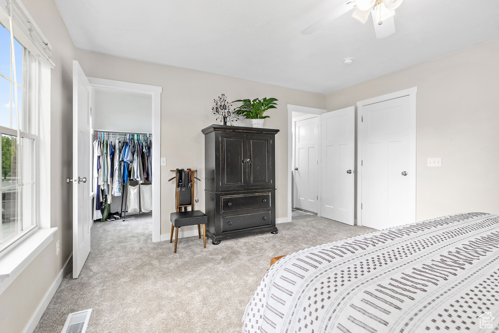 Bedroom featuring light carpet, baseboards, a spacious closet, a closet, and ceiling fan
