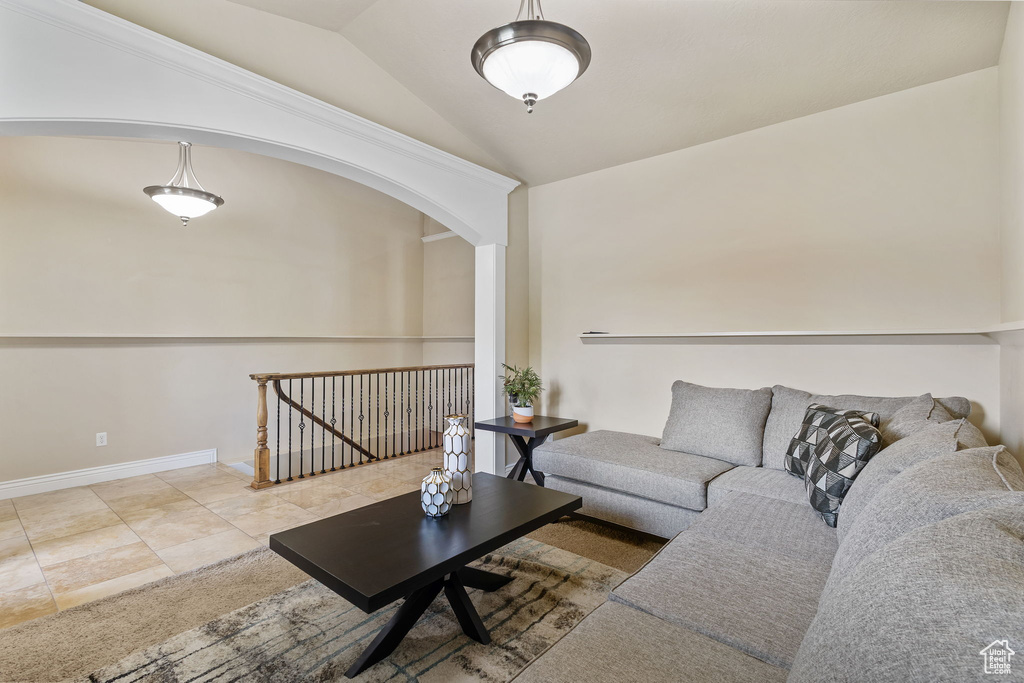 Tiled living area with lofted ceiling, arched walkways, and baseboards