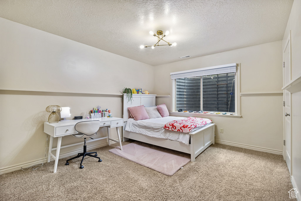 Carpeted bedroom featuring a chandelier, a textured ceiling, and baseboards