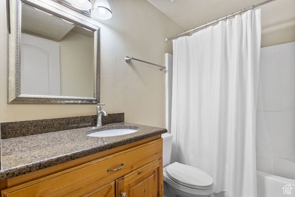 Bathroom featuring toilet, vanity, and shower / bath combo with shower curtain