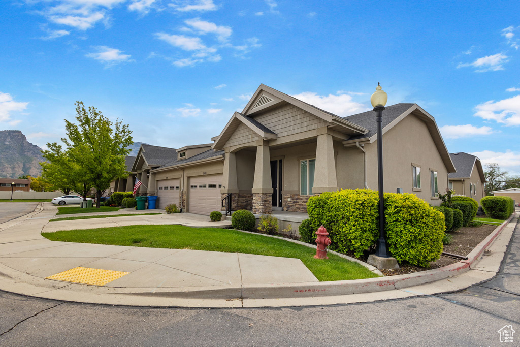 Craftsman inspired home with an attached garage, stucco siding, concrete driveway, a front lawn, and stone siding