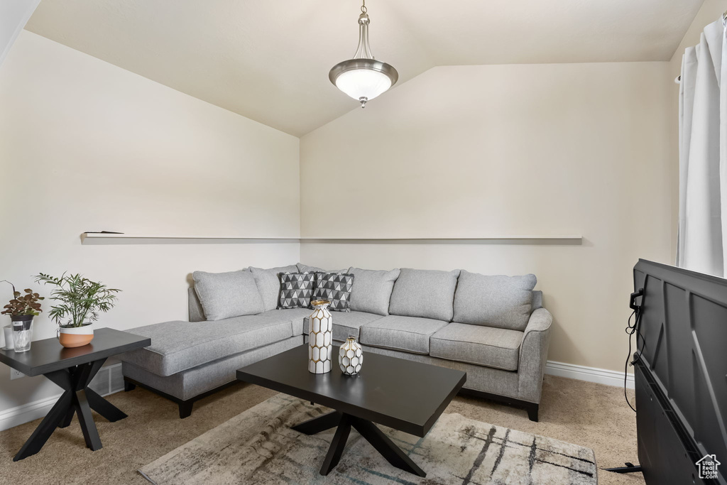 Living area featuring lofted ceiling, baseboards, and light colored carpet