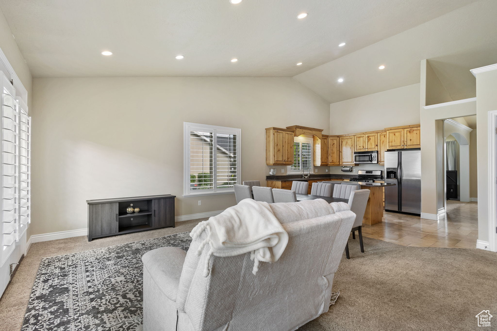 Living room with baseboards, high vaulted ceiling, light carpet, and recessed lighting