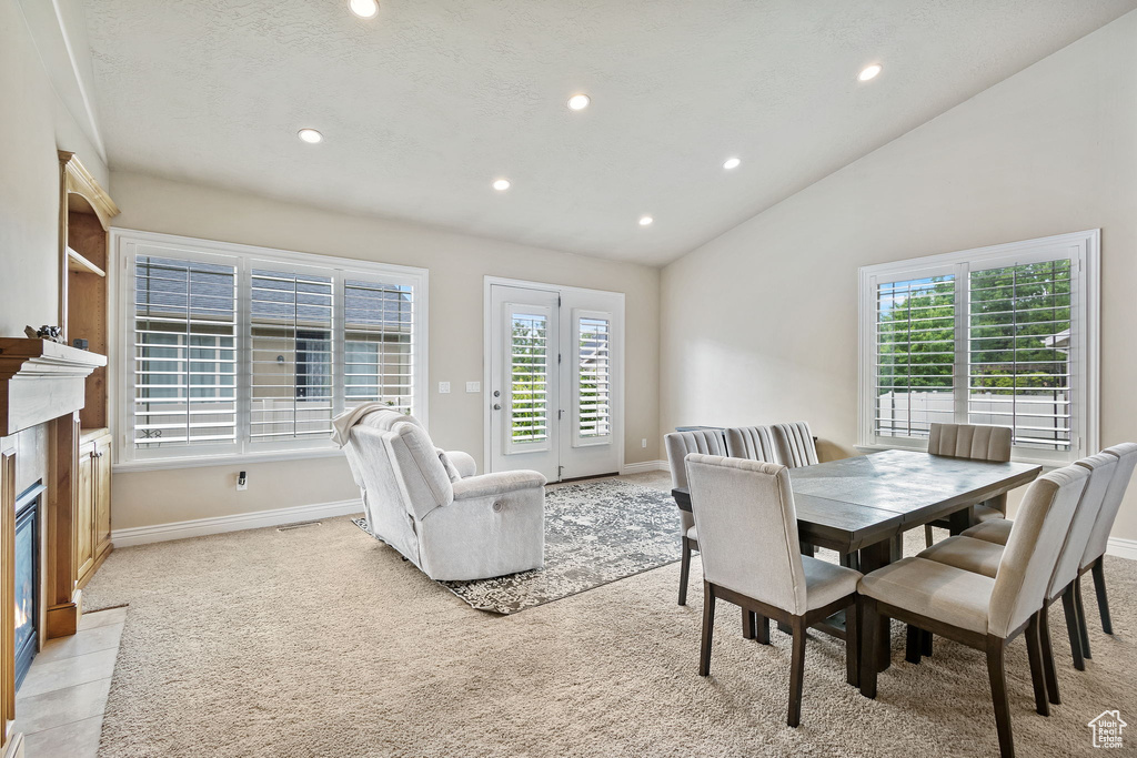 Dining area featuring recessed lighting, light colored carpet, baseboards, vaulted ceiling, and a fireplace