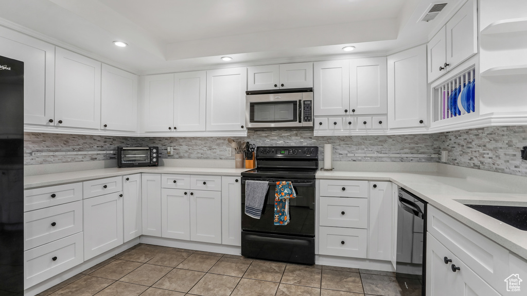 Kitchen with black appliances, white cabinetry, light tile patterned floors, backsplash, and light countertops