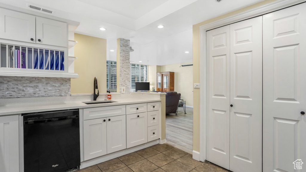 Kitchen featuring dishwasher, a sink, white cabinets, light countertops, and recessed lighting