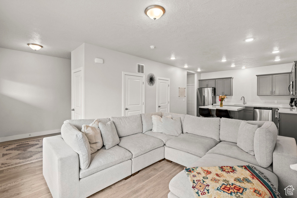 Living area featuring light wood-style flooring, baseboards, and recessed lighting