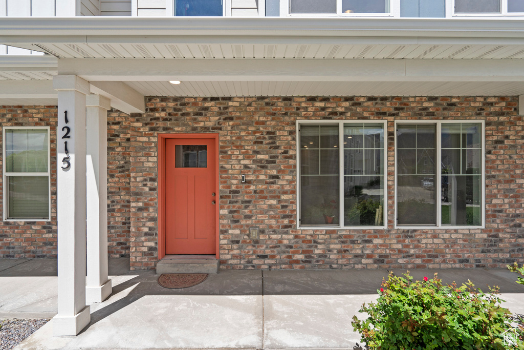 View of exterior entry with covered porch and brick siding