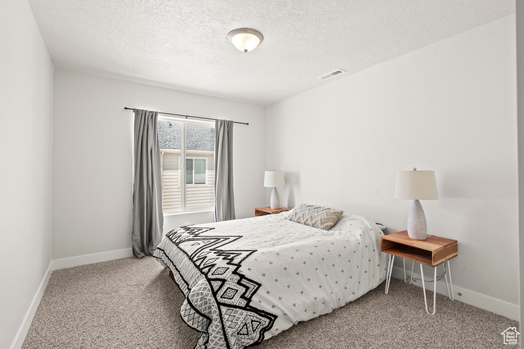 Bedroom with carpet flooring, a textured ceiling, and baseboards