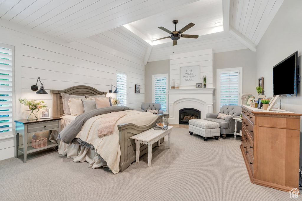 Bedroom featuring carpet floors, lofted ceiling, a fireplace, wood walls, and a ceiling fan