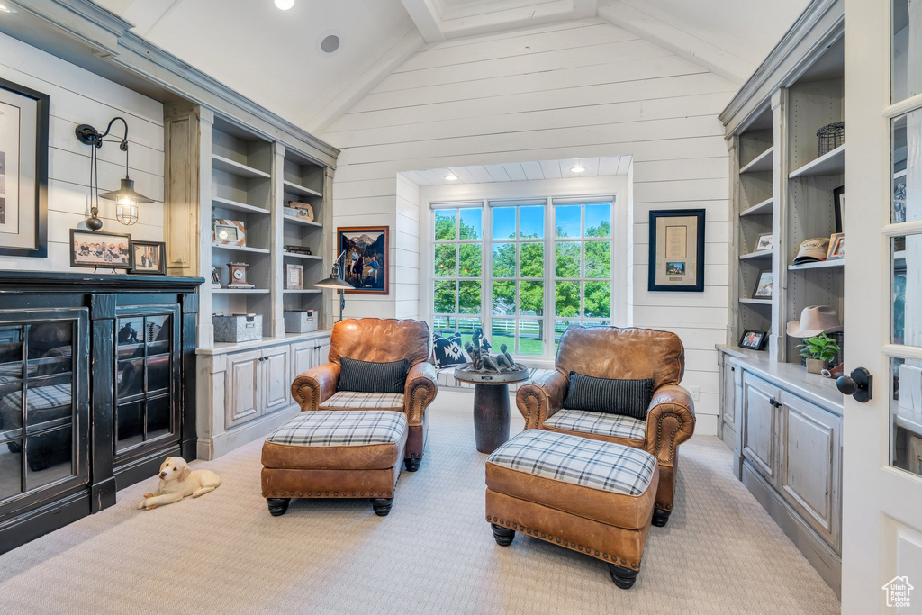Sitting room with vaulted ceiling, carpet flooring, and wooden walls