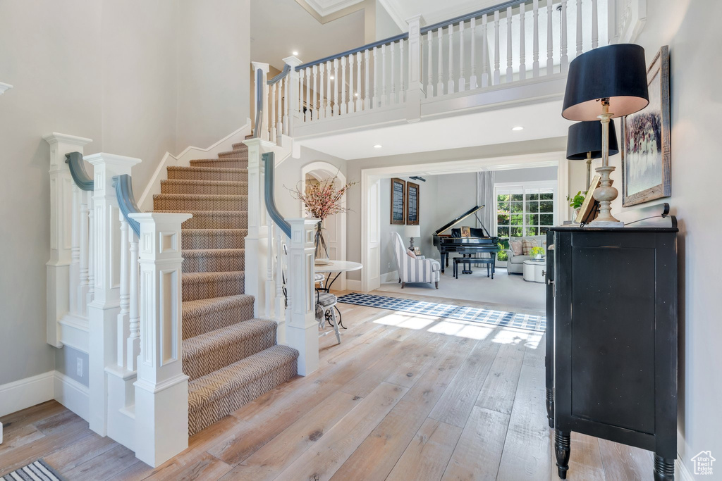 Foyer entrance with wood-type flooring, a high ceiling, stairway, and baseboards