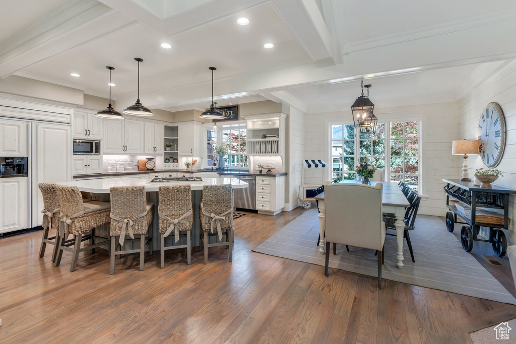 Kitchen featuring open shelves, built in appliances, wood finished floors, white cabinetry, and backsplash