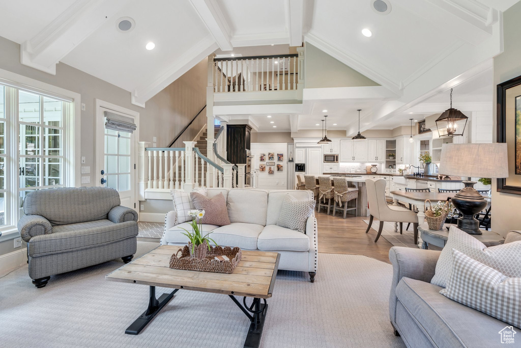 Living room featuring beamed ceiling, stairway, wood finished floors, high vaulted ceiling, and a chandelier