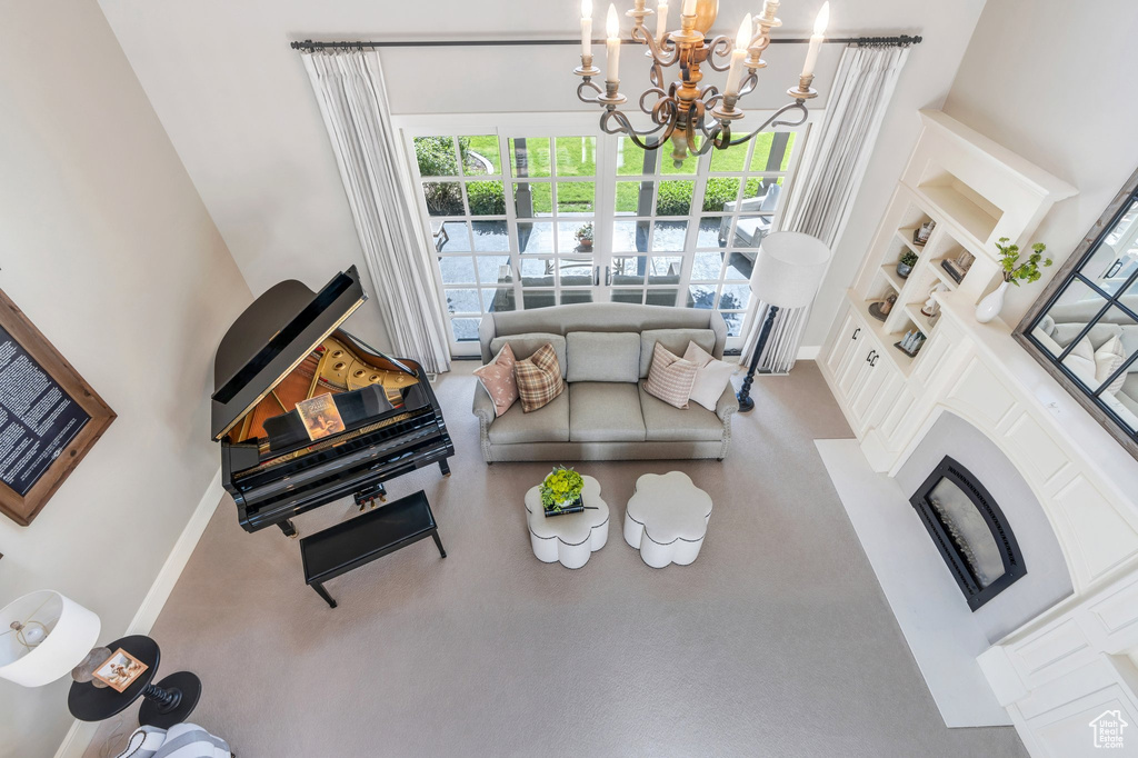 Living area featuring a chandelier, built in features, baseboards, and a high ceiling