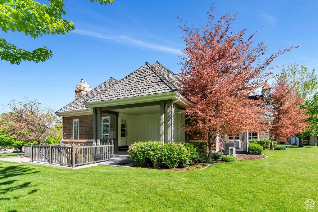 Rear view of property featuring a yard, a chimney, central AC, and a deck