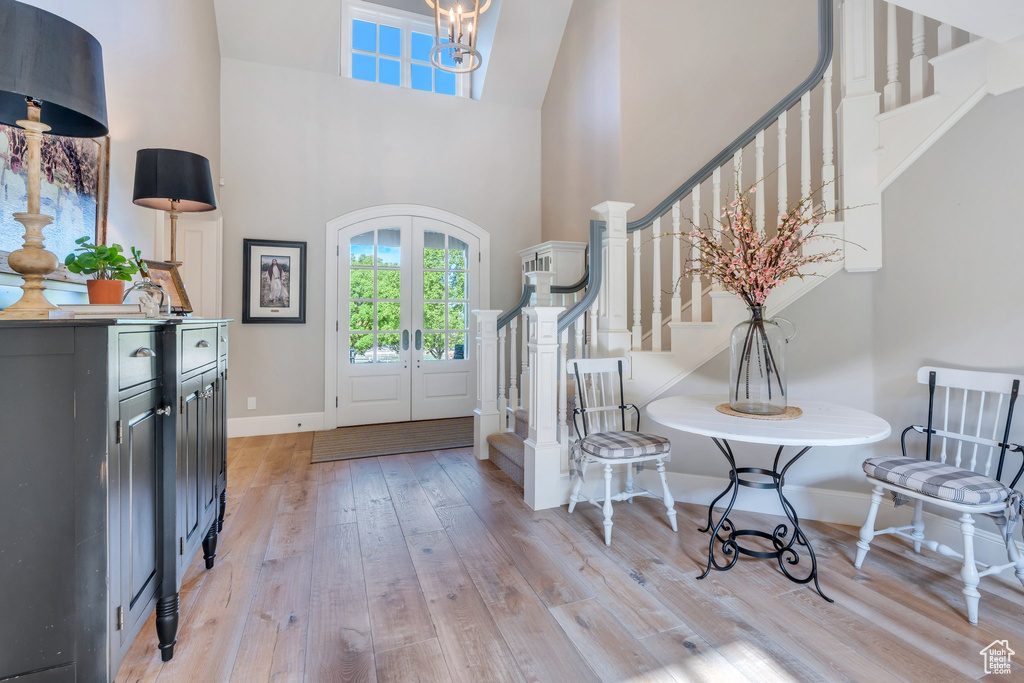 Foyer entrance featuring stairway, french doors, light wood-style floors, a high ceiling, and baseboards