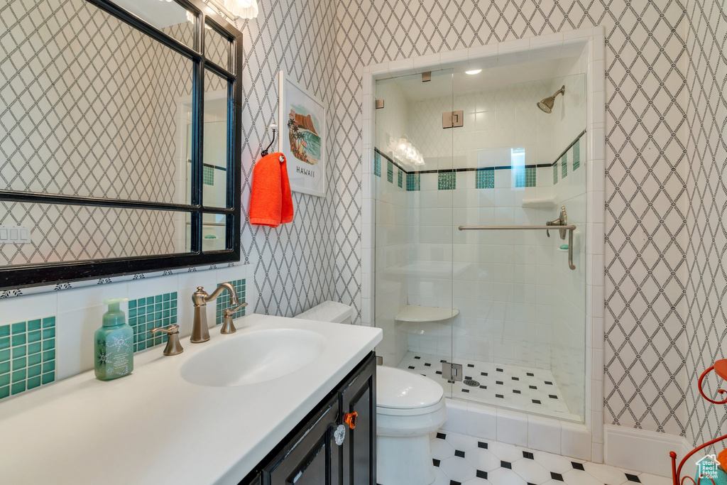 Bathroom with wallpapered walls, a stall shower, toilet, and vanity