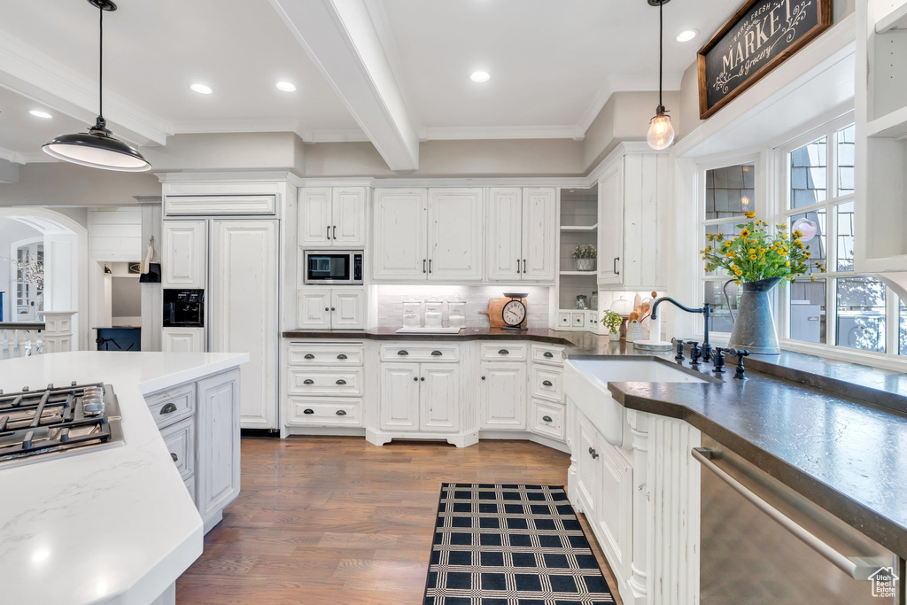 Kitchen featuring built in appliances, a sink, crown molding, backsplash, and white cabinets