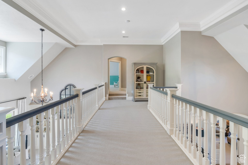 Hallway with an upstairs landing, light carpet, a chandelier, ornamental molding, and recessed lighting