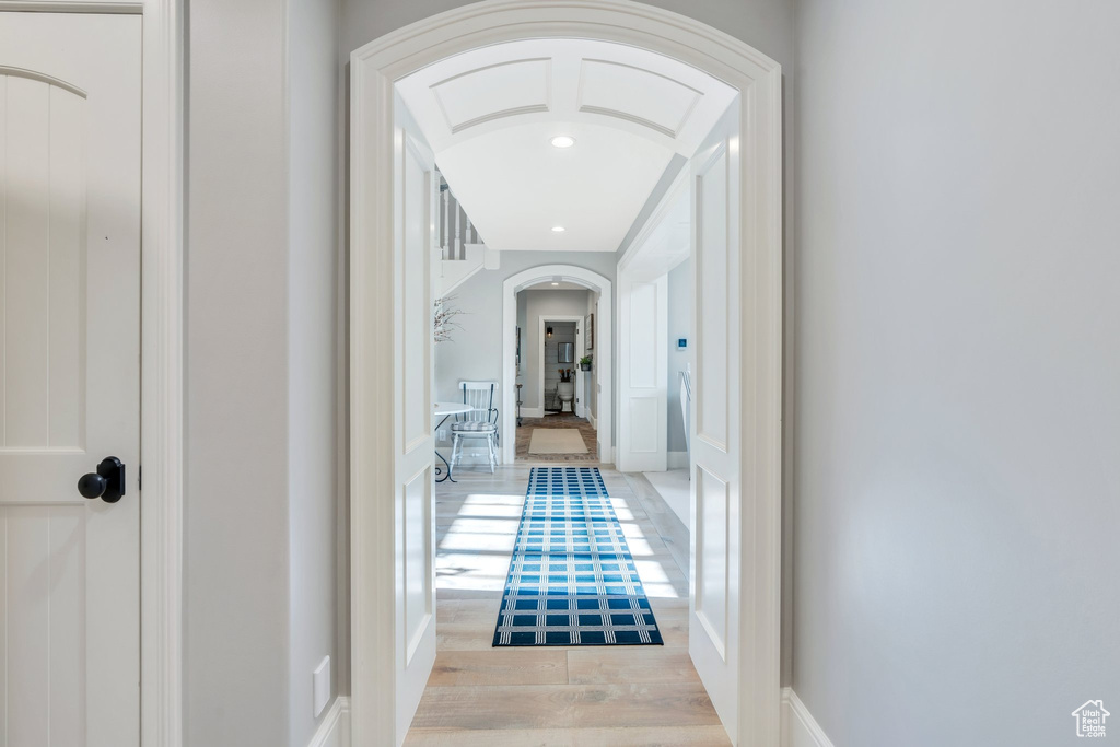 Hall with arched walkways, light wood-style floors, and recessed lighting