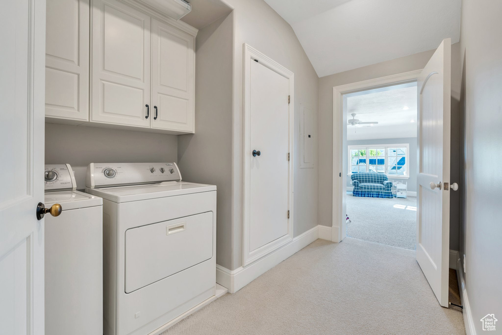 Washroom featuring washer and dryer, light carpet, cabinet space, and baseboards