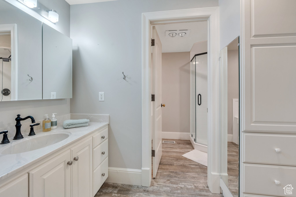 Bathroom with wood finished floors, a stall shower, vanity, and baseboards