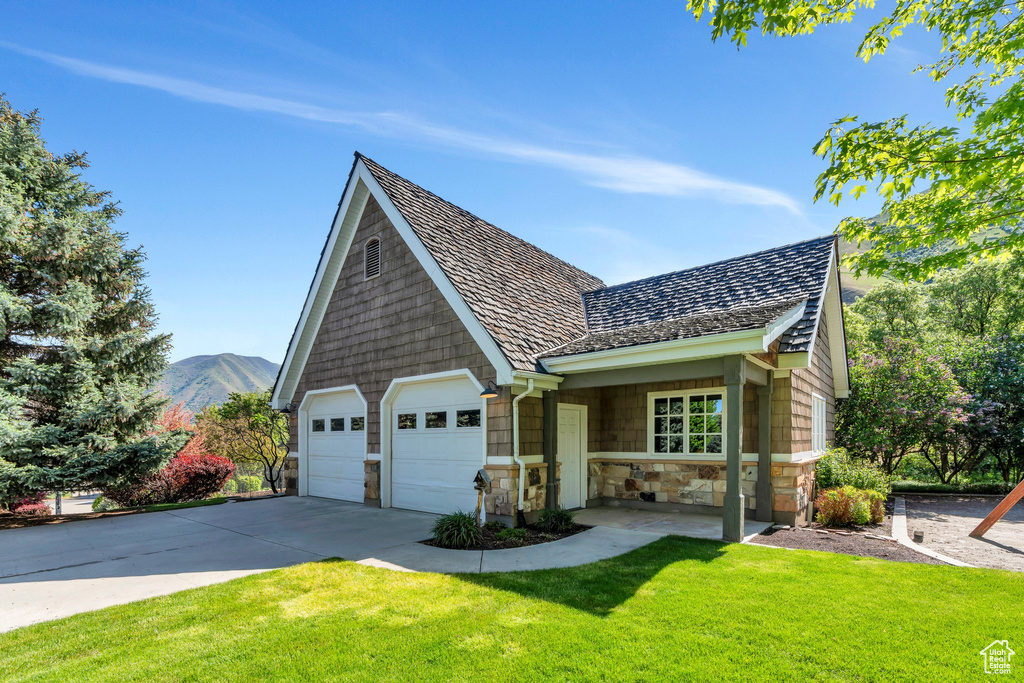 View of front of property featuring stone siding, a front yard, driveway, and a mountain view